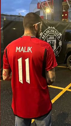 a man in a red shirt standing next to a truck with the number 11 on it