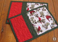 two quilted placemats sitting on top of a wooden floor next to each other