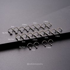 a set of six pairs of nose rings with different sizes and widths on a black background