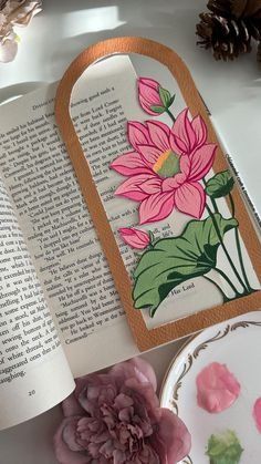 an open book sitting on top of a white table next to flowers and other items