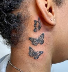 the back of a man's neck has three butterflies on it and behind his ear is a chain