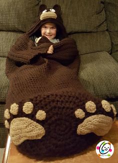 a child wrapped in a bear blanket on top of a table next to a couch