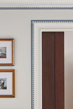 framed pictures hang on the wall next to a doorway with an open door and brown wooden door