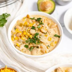 two bowls filled with soup next to an avocado and other foods on the table