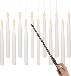 a person is holding a wand in front of many white candles that are hanging from the ceiling