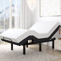 an adjustable bed frame in a living room with white walls and flooring on the side