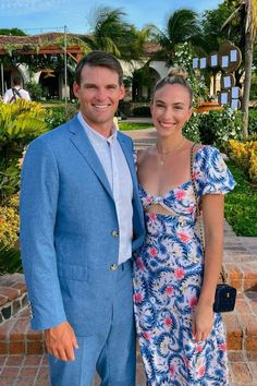 a man and woman standing next to each other in front of a building with palm trees