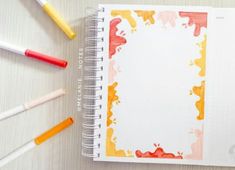 an open notebook with paint splattered on it and colored pencils next to it