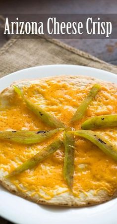 a white plate topped with an omelet covered in cheese and green beans next to a napkin