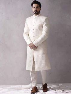 Item Contains:  Sherwani kurta and Pants   Color :  white Fabric :  Quilted silk fabric Style and Designs :  sherwani has mandarin collar and long sleeves with a full button placket even hem and multiple straight slits Kurta has mandarin collar and long sleeves with symmetric hem and multiple slits Pants boot cut style pants with 2 pockets and a fly on zip and hooks  Size :  Slim fit  Model height is 6 fit and wearing 40 size  Material and Care :  Polyester mix  Only dry clean  Note :  There mig White Fitted Bandhgala For Groom, White Long Sherwani For Eid, White Fitted Sherwani For Eid, White Fitted Kurta For Groom, Fitted White Sherwani For Groom, White Fitted Sherwani For Groom, White Fitted Sherwani For Winter, White Long Bandhgala With Dabka, Fitted White Winter Sherwani