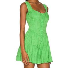 This Emerald Bay Everly Romper Mini Dress From Pq Swim / Pilyq In Kelly Green Swiss Dot Is Woven With Shimmering Gold Threads. This Piece Looks Like A Button Front Mini Dress But Is Actually A Romper! It Catches The Light Beautifully, Adding A Touch Of Glamour To Your Look. It Has Wide Shoulder Straps, Front-Covered Buttons, A Flattering V-Waist, Gorgeous Bustier / Corset Seaming, And A Tiered Pleated Mini Skirt That Create A Flirty And Playful Silhouette, Perfect For Any Daytime Adventure Or Ev Chic Green Rayon Mini Dress, Green Mini Dress For Beach Cover-up, Playful Fitted Green Bubble Romper, Green Short Sleeve Playwear Dress, Green Sleeveless Mini Dress For Beach Cover-up, Emerald Bay, Swiss Dot, Gold Threads, Pleated Mini Skirt