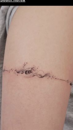 a woman's arm with a small wave tattoo on it