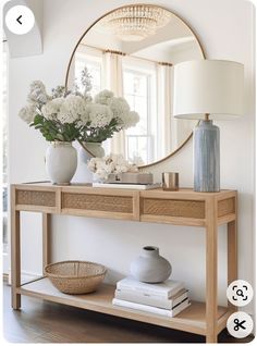 a console table with flowers on it and a round mirror above the top that says,