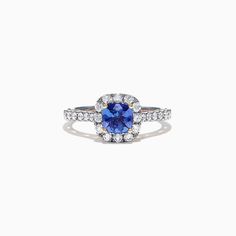 an oval blue sapphire and diamond ring on a white background, with the center stone surrounded by smaller round diamonds