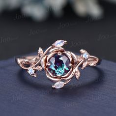 a ring with an oval blue stone surrounded by leaves and diamonds on a black surface