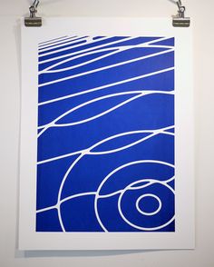 a blue and white art print hanging on a wall next to two hooks with clothes pins