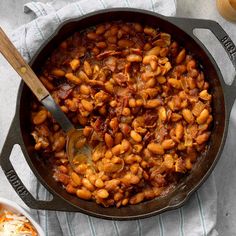 a skillet filled with baked beans next to a bowl of mashed potatoes