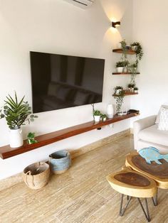 a flat screen tv mounted on the wall in a living room next to two stools