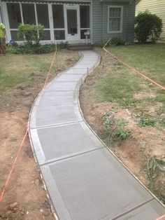 a concrete walkway is being laid in front of a house