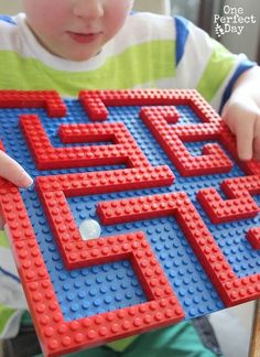 a young boy holding a toy made out of legos that look like he is playing with