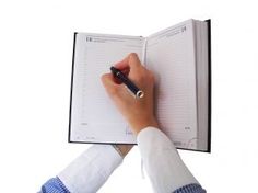 a person writing on a notebook with a pen in their left hand and the other hand holding a clipboard