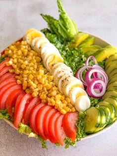 a salad with tomatoes, cucumbers, corn and lettuce on it