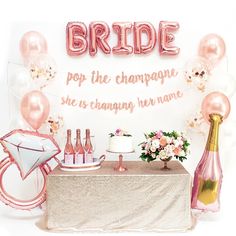 a table topped with balloons and bottles filled with champagne next to a sign that says bride pop the champagne she's changing her name