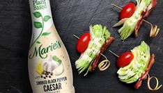 three small sandwiches with tomatoes and lettuce on skewers next to a bottle of mayonnaise