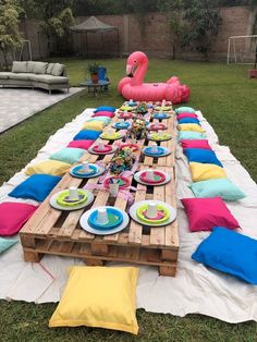 a table set up with plates and pink flamingo floater in the back yard