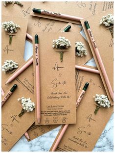 wedding stationery with flowers and pencils laid out on top of each other for guests to sign