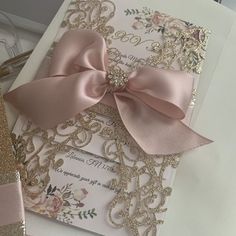 a pink and gold wedding card with a bow