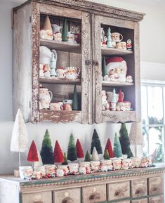 an old china cabinet is decorated with christmas trees and santa hats on the top shelf