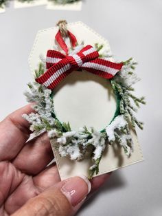 a hand holding a christmas wreath ornament