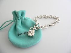 Offered for sale is a wonderful and super cute Tiffany and Co. Sterling Silver Signature Gift Box Charm bracelet.   The piece is made from substantial and bright Tiffany silver, and yet retains a very feminine feel to it.  Attached to its very substantial and bright Tiffany Silver charm bracelet is a super Cool Signature Gift Box Padlock charm.  The Gift Box padlock charm is permanently attached to the bracelet - so you will not ever have the risk of losing the charm!  It is a classic Tiffany pi Luxury Silver Jewelry For Birthday Gift, Luxury Silver Jewelry With Original Box, Rectangular Bracelet With Box Clasp As Gift, Rectangular Bracelet With Box Clasp For Gift, Elegant Jewelry With Box Clasp For Gift, Elegant Jewelry Gift With Box Clasp, Designer White Gold Jewelry For Gifts, Designer White Gold Jewelry Gift, Designer Silver Jewelry With Original Box