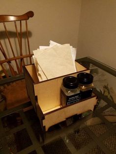 a wooden chair sitting next to a box filled with jars and paper towels on top of a tiled floor