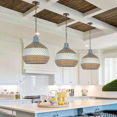 three pendant lights hanging from the ceiling above a kitchen island with stools and breakfast bar