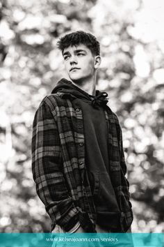 a young man is standing in front of trees