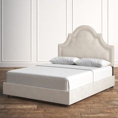 a white bed sitting on top of a wooden floor