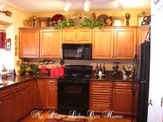 a kitchen with wooden cabinets, black appliances and lots of holiday decorations on the wall