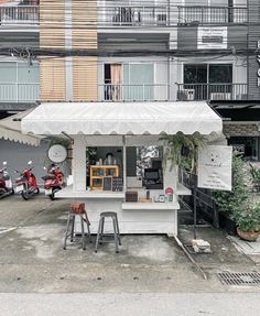 a small white building with two mopeds parked in front of it and an awning over the entrance