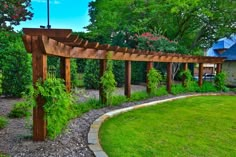 a wooden arbor in the middle of a yard with green grass and trees around it