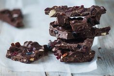 several pieces of chocolate are stacked on top of each other with cranberries and nuts