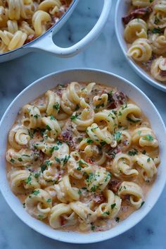 two bowls filled with macaroni and cheese on top of a marble countertop