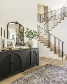 a living room with a large rug and stairs