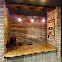 a kitchen with brick walls and wooden counter tops, lights on above the bar area