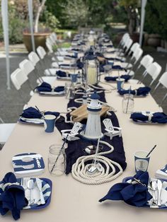 a long table is set with blue and white plates, napkins and utensils