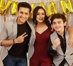 two men and a woman posing for a photo in front of gold balloons with the word happy on it