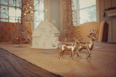 two gold deer figurines sitting on top of a table next to a christmas tree