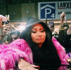 a woman in a pink fur coat is surrounded by people