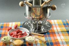 there is a bowl of fruit and dips next to a pot on the table